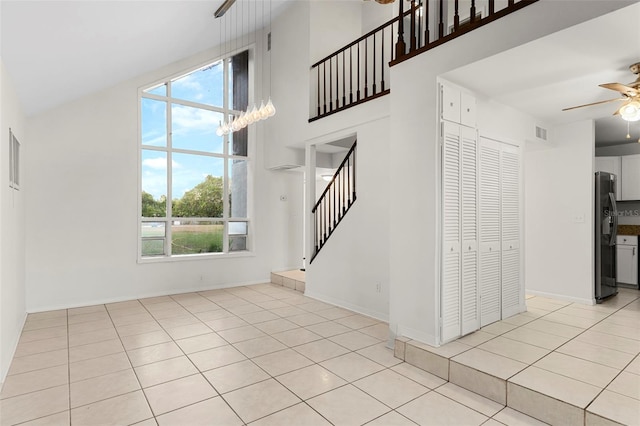 interior space featuring stairway, ceiling fan, plenty of natural light, and a towering ceiling