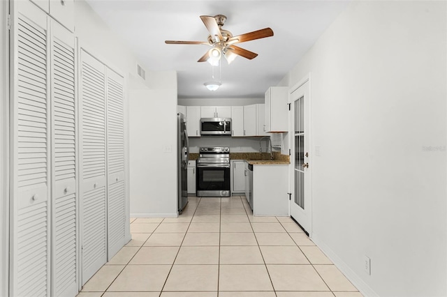 kitchen featuring light tile patterned floors, ceiling fan, a sink, white cabinetry, and stainless steel appliances