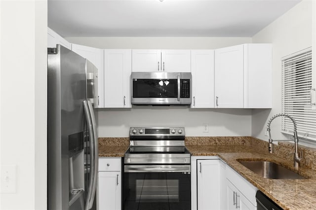 kitchen featuring stone countertops, appliances with stainless steel finishes, white cabinetry, and a sink