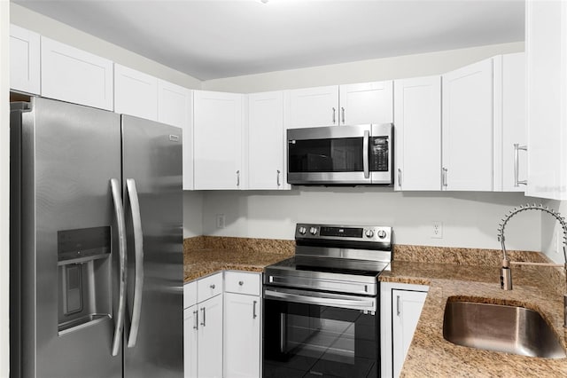 kitchen with white cabinets, stone countertops, appliances with stainless steel finishes, and a sink