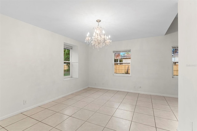 spare room with light tile patterned floors, baseboards, and a chandelier