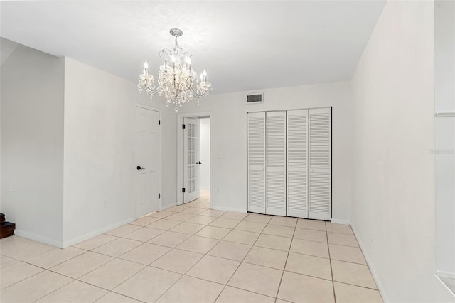 unfurnished bedroom with a chandelier, light tile patterned flooring, baseboards, and visible vents