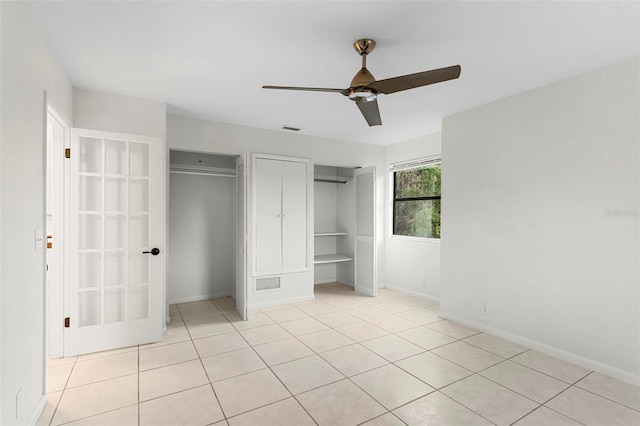 unfurnished bedroom featuring light tile patterned flooring, multiple closets, visible vents, ceiling fan, and baseboards