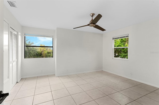 unfurnished room with ceiling fan, light tile patterned flooring, baseboards, and visible vents