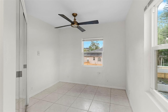 empty room featuring ceiling fan, light tile patterned floors, and a healthy amount of sunlight