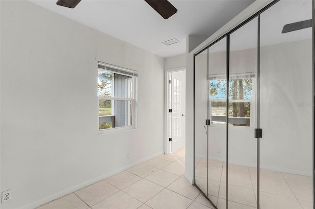 interior space featuring light tile patterned floors, visible vents, baseboards, and ceiling fan
