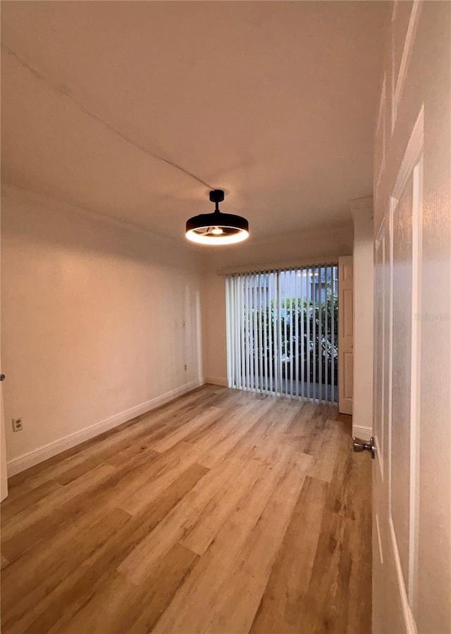 spare room featuring light wood-type flooring and baseboards