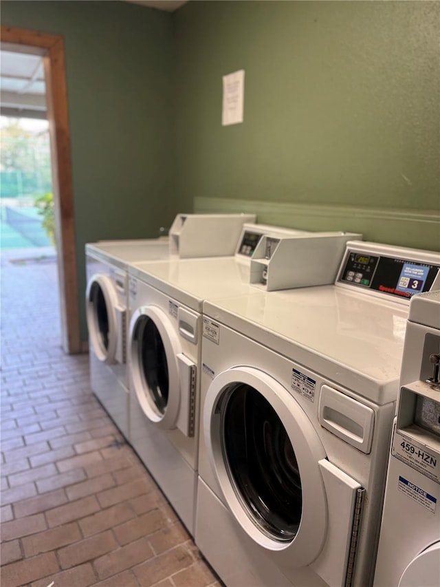 community laundry room featuring separate washer and dryer and brick floor