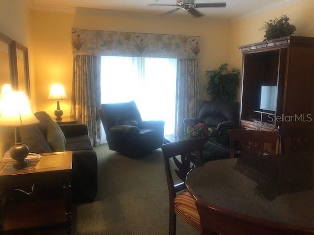 carpeted living area featuring ornamental molding and a ceiling fan