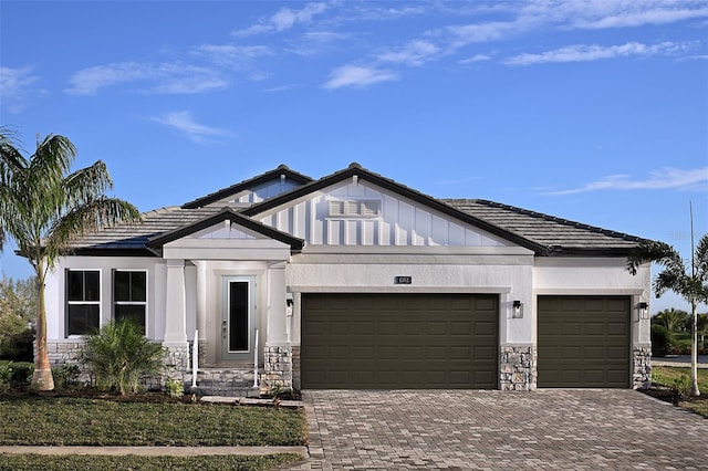 view of front of property featuring a garage, stone siding, decorative driveway, and stucco siding