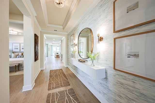 corridor with baseboards, a raised ceiling, wood finished floors, and crown molding