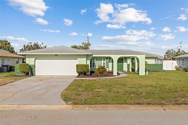 view of front of property with stucco siding, concrete driveway, a front yard, fence, and a garage