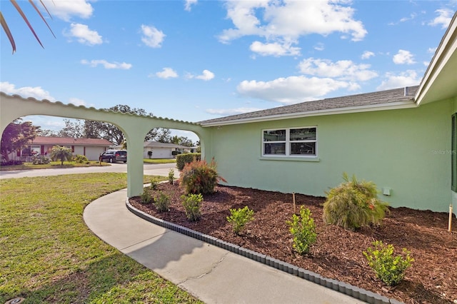 view of side of property with a lawn and stucco siding