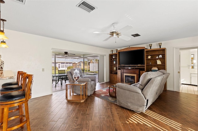 living room with a glass covered fireplace, visible vents, and wood finished floors