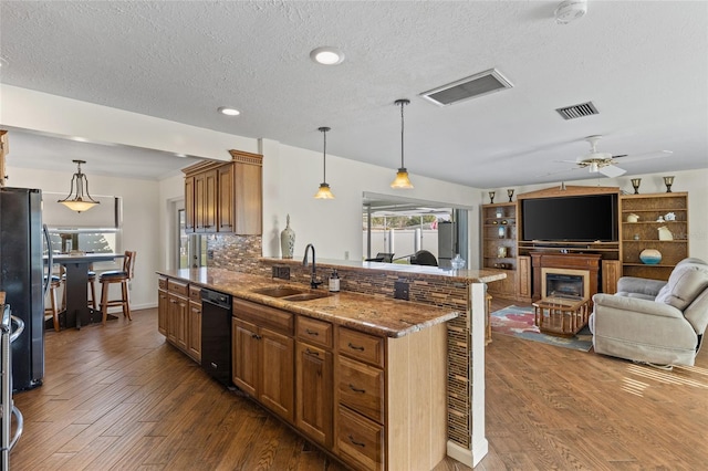 kitchen with visible vents, backsplash, freestanding refrigerator, a sink, and wood finished floors