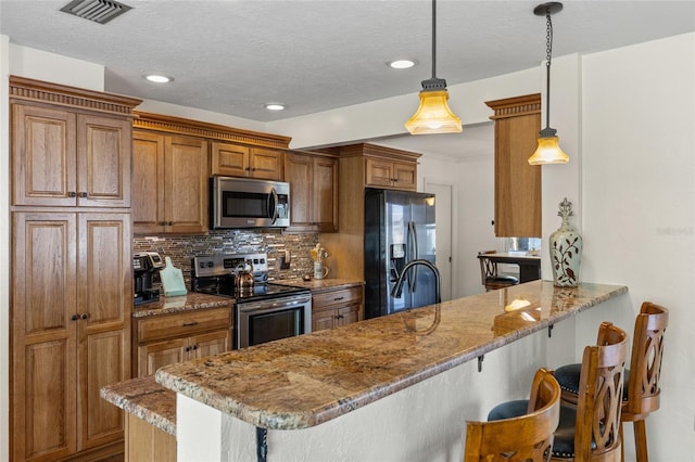 kitchen featuring a peninsula, a breakfast bar, visible vents, appliances with stainless steel finishes, and backsplash