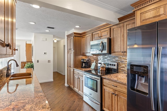 kitchen featuring dark wood-style flooring, stainless steel appliances, visible vents, backsplash, and a sink