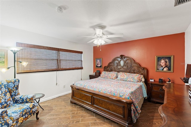 bedroom featuring a ceiling fan, wood finished floors, visible vents, and baseboards