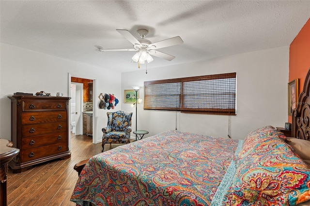 bedroom featuring a ceiling fan, connected bathroom, a textured ceiling, and wood finished floors