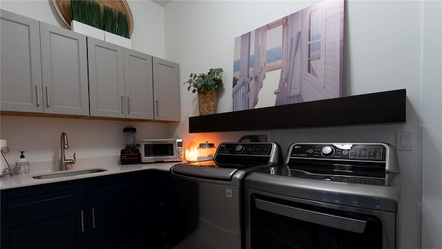 washroom featuring a toaster, a sink, washing machine and clothes dryer, and cabinet space