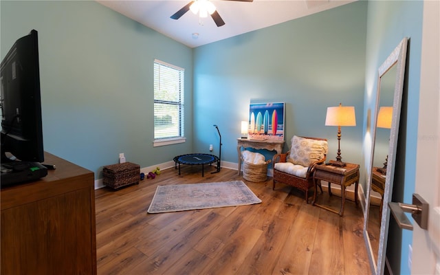 living area with baseboards, ceiling fan, and light wood-style floors