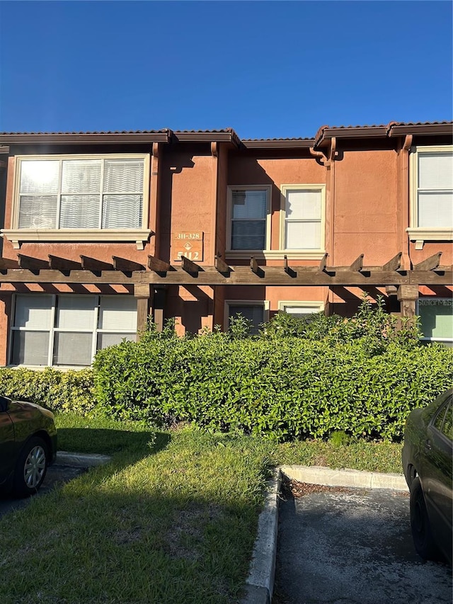 view of front facade featuring uncovered parking, a tile roof, and stucco siding