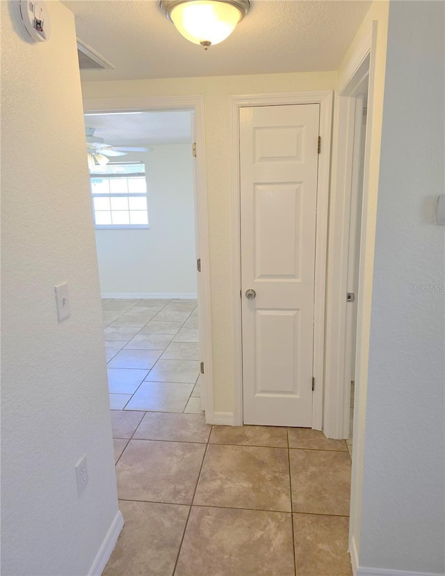 hall featuring baseboards and light tile patterned floors