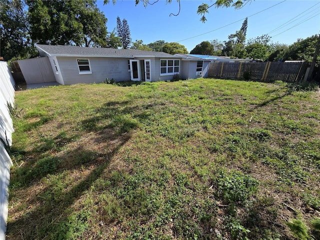 rear view of property with a fenced backyard and a yard