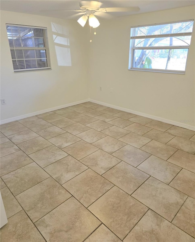 empty room featuring light tile patterned floors, baseboards, and ceiling fan