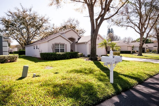 view of front facade with stucco siding, concrete driveway, a garage, a residential view, and a front lawn