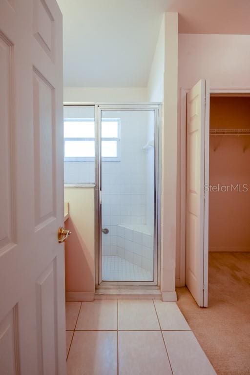 full bathroom with a spacious closet, tile patterned flooring, and a shower stall