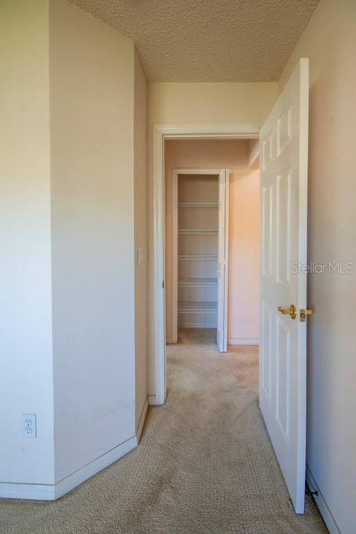 hall with carpet, baseboards, and a textured ceiling