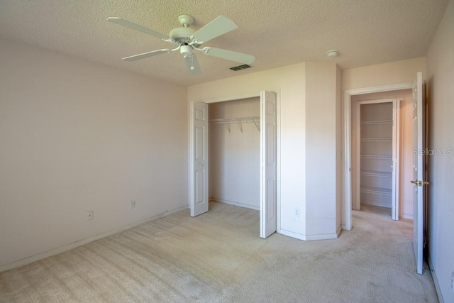 unfurnished bedroom featuring light carpet, a textured ceiling, visible vents, and a ceiling fan