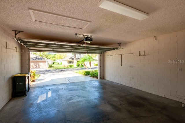 garage with a garage door opener and concrete block wall