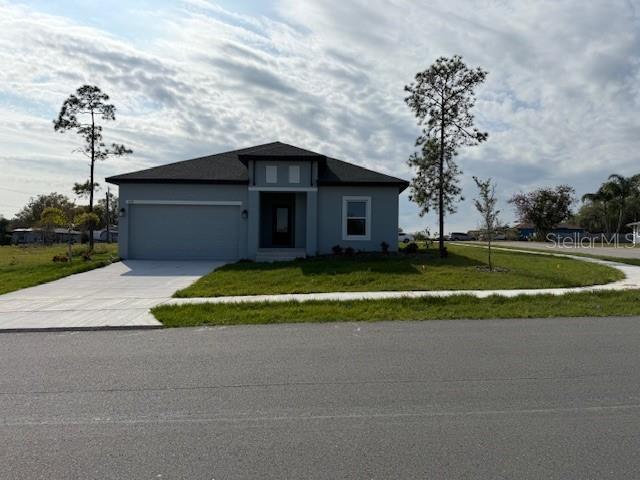 view of front of house featuring a front yard, concrete driveway, and an attached garage