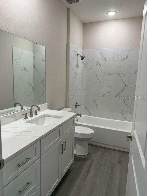 bathroom with vanity, toilet, wood finished floors, and bathtub / shower combination