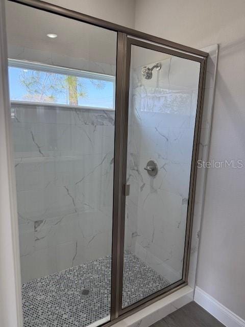 full bathroom featuring a shower stall and baseboards