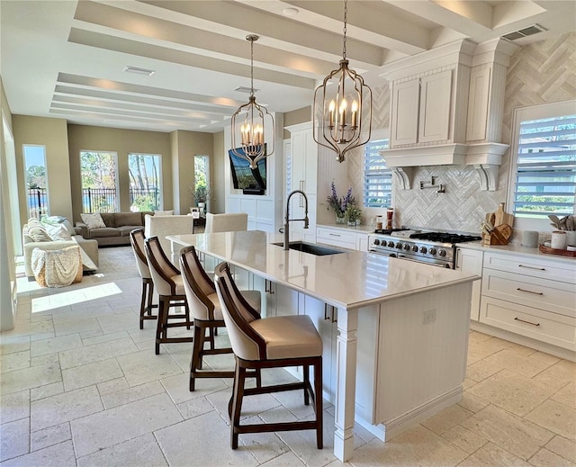 kitchen featuring stone tile floors, visible vents, stainless steel stove, and a sink