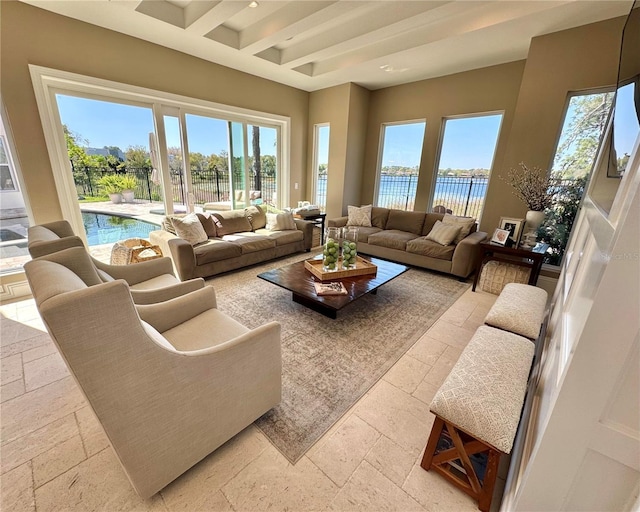 living area with beam ceiling, plenty of natural light, a water view, and stone tile flooring