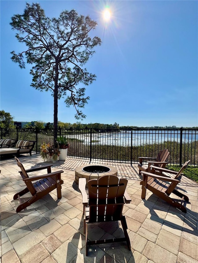 view of patio featuring fence, a water view, and an outdoor fire pit