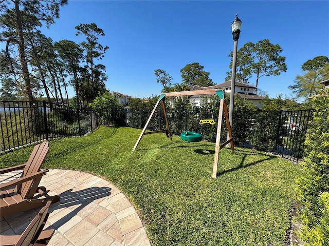 view of playground with a yard, a fenced backyard, and a patio area