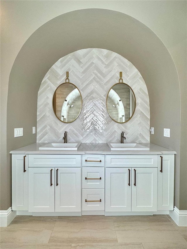 full bathroom with double vanity, backsplash, and a sink