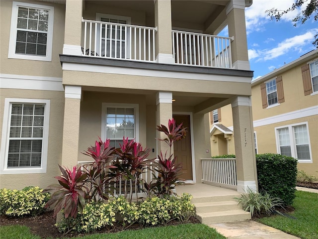 view of exterior entry with covered porch and stucco siding