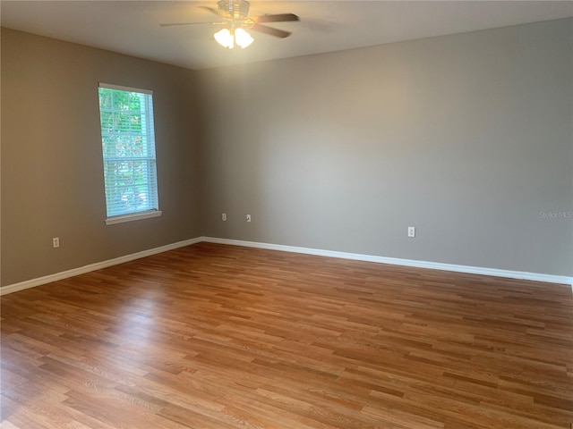 spare room featuring baseboards, light wood-type flooring, and ceiling fan