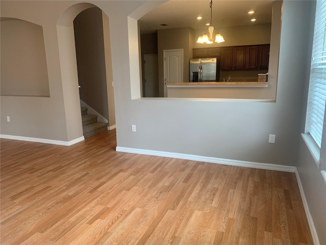 unfurnished room with stairway, baseboards, and light wood finished floors