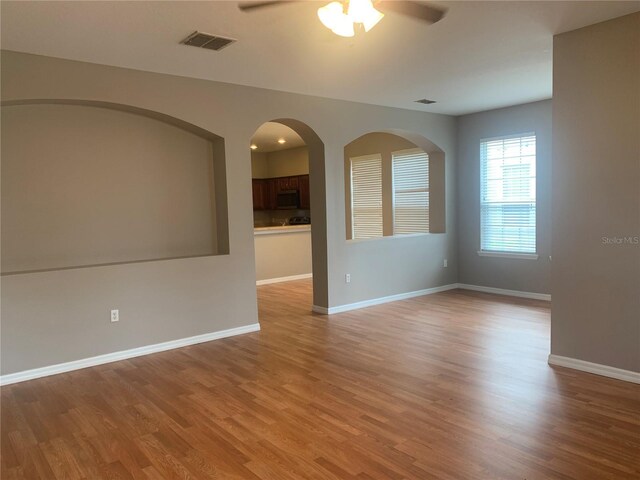 spare room featuring ceiling fan, visible vents, baseboards, and wood finished floors