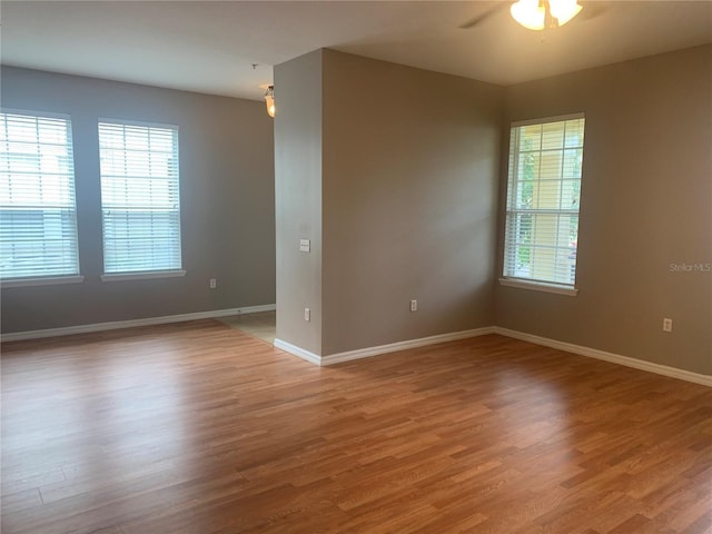 empty room featuring baseboards, a ceiling fan, and light wood finished floors