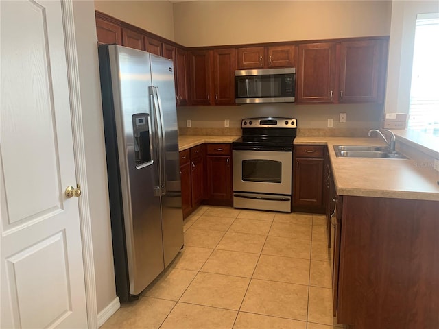 kitchen with a sink, light countertops, light tile patterned flooring, and stainless steel appliances