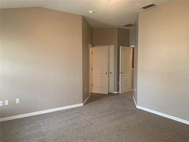 carpeted empty room with visible vents, baseboards, and vaulted ceiling