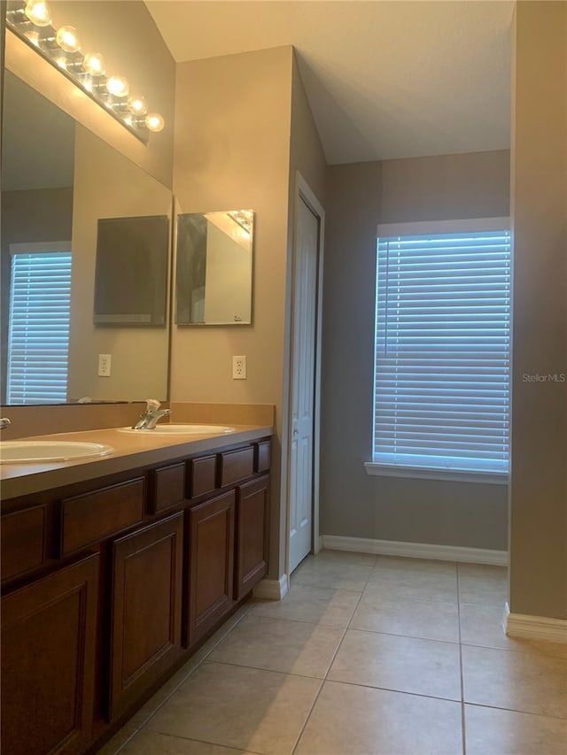 full bathroom featuring a sink, baseboards, double vanity, and tile patterned flooring